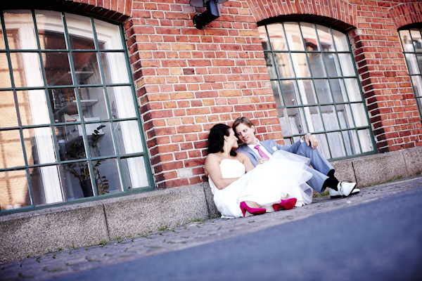 the happy couple sitting against wall in urban setting - wedding photo by top Swedish wedding photographers Dayfotografi