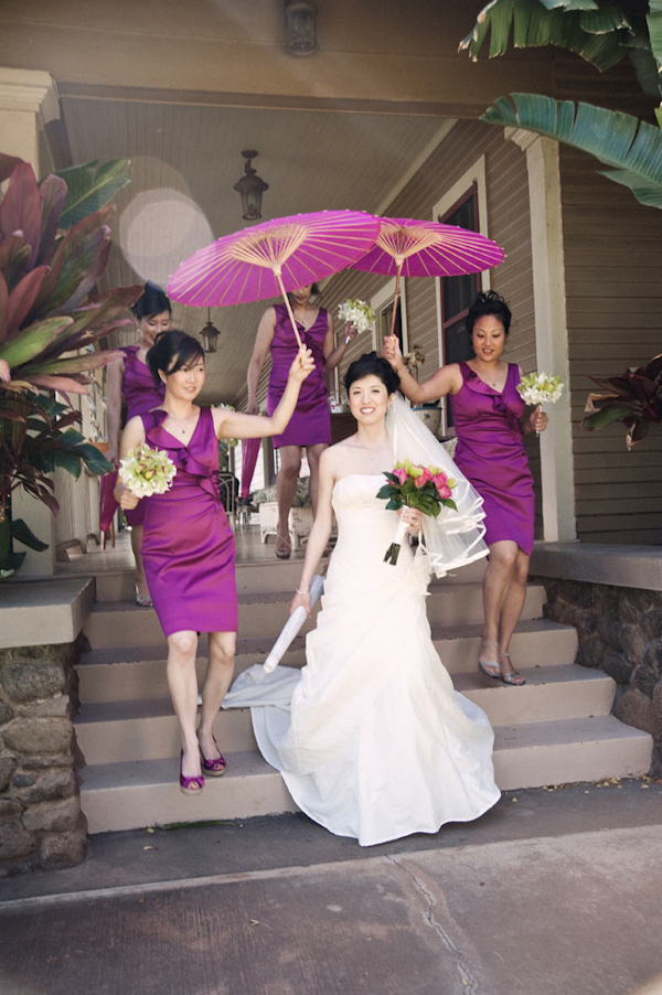 bride walking with bridesmaids in purple dresses, carrying purple parasols - photo by Hawaii based wedding photographer Derek Wong