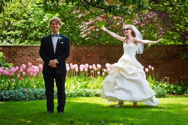 fun image of the bride and groom playing around in a garden of tulips - the bride is wearing a white ball-gown style dress wearing sunglasses - photo by Washington DC based wedding photographers Holland Photo Arts