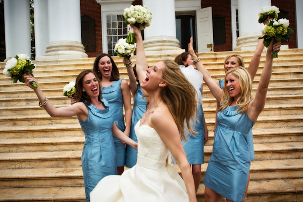 the bride and her bridesmaids in blue dresses holding up their white and green floral bouquets in the air - photo by Washington DC based wedding photographers Holland Photo Arts