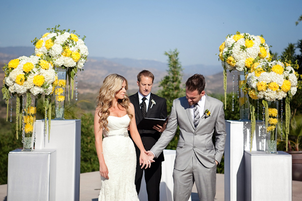 Beautiful sunny, outdoor wedding ceremony with white and yellow floral arrangements - Photo by April Smith & Co.