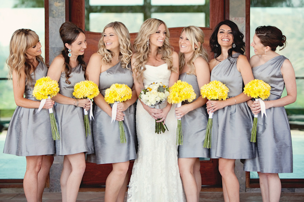 Joyful photo of the bride and bridesmaids, wearing short gray dresses with yellow bouquets - Photo by April Smith & Co.