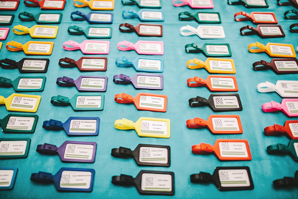 Brightly colored luggage tags as seating placecards -wedding photo by Benj Haisch
