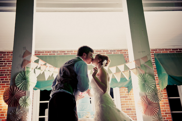 Bride and groom in front of pastel-colored wedding decor - Wedding Photo by Elizabeth Davis