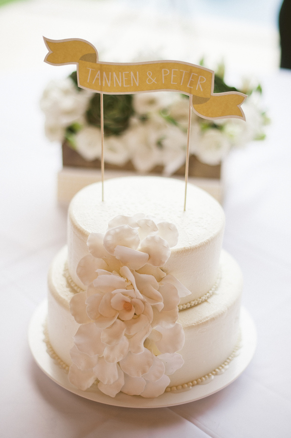 Simple two-tiered white wedding cake with customized banner cake topper - Photo by Jillian Mitchell