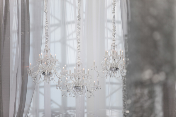 Wedding Photo by Miller and Miller Photography of reception decor with crystal chandeliers and grey curtains