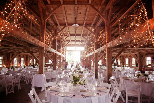 Rustic barn wedding with twinkling lights and elegant white decor - Photo by Emily Delamater