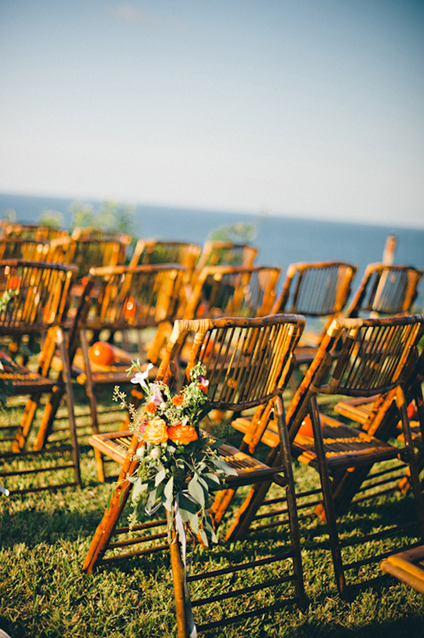 wooden chairs with orange floral arrangements at seaside ceremony site - Sayulita, Mexico destination wedding photo by Mexico wedding photographer Jillian Mitchell