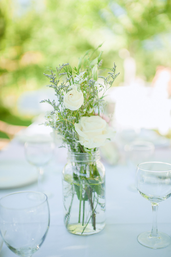 Simple white roses and greenery as reception table arrangement - Photo by Nordica Photography