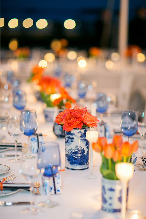 Beautiful tabletop with bright orange flowers and blue and white vases - Photo by Sarah Tew Photography