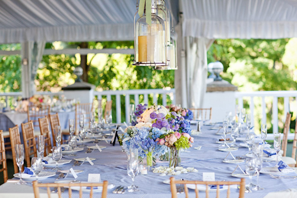 long light blue table setting with flower centerpieces and glass lanterns hanging above - preppy New York Sagamore resort wedding photo by New York wedding photographer Tracey Buyce