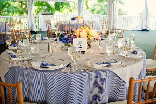 blue pinstripe table cloth under white tablecloth preppy table setting in covered outdoor reception area - preppy New York Sagamore resort wedding photo by New York wedding photographer Tracey Buyce