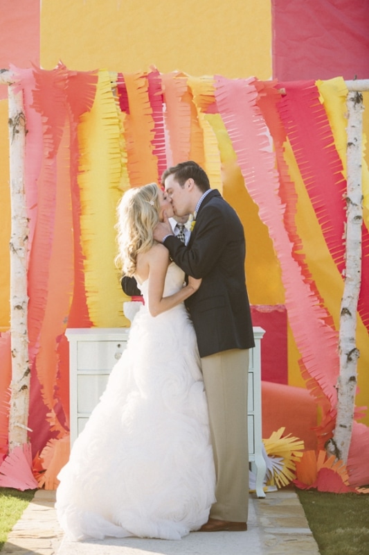colorful pink, orange yellow streamer backdrop at wedding ceremony, photo by Taylor Lord Photography