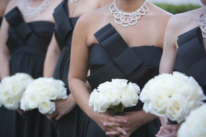 bridesmaids with long black dresses with large bow and white rose bouquets, photo by JSPStudio