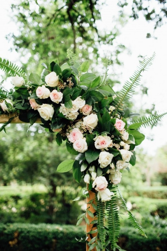 ceremony arch with light pink floral design and ferns