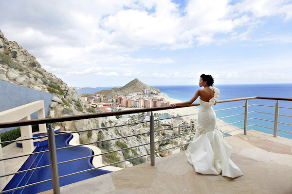 bride standing on balcony overlooking beautiful Cabo San Lucas Mexico - photo by top destination wedding photographers Chris plus Lynn photography bride standing on balcony overlooking beautiful Cabo San Lucas Mexico - photo by top destination wedding photographers Chris plus Lynn photography