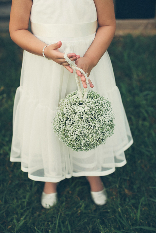 Flower girl in white dress with white and green pomander - Photo by The Schultzes