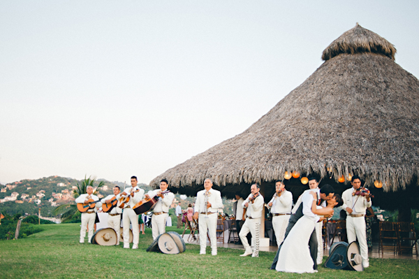 the couple kisses in front of a mariachi band and their reception site - Sayulita, Mexico destination wedding photo by Mexico wedding photographer Jillian Mitchell