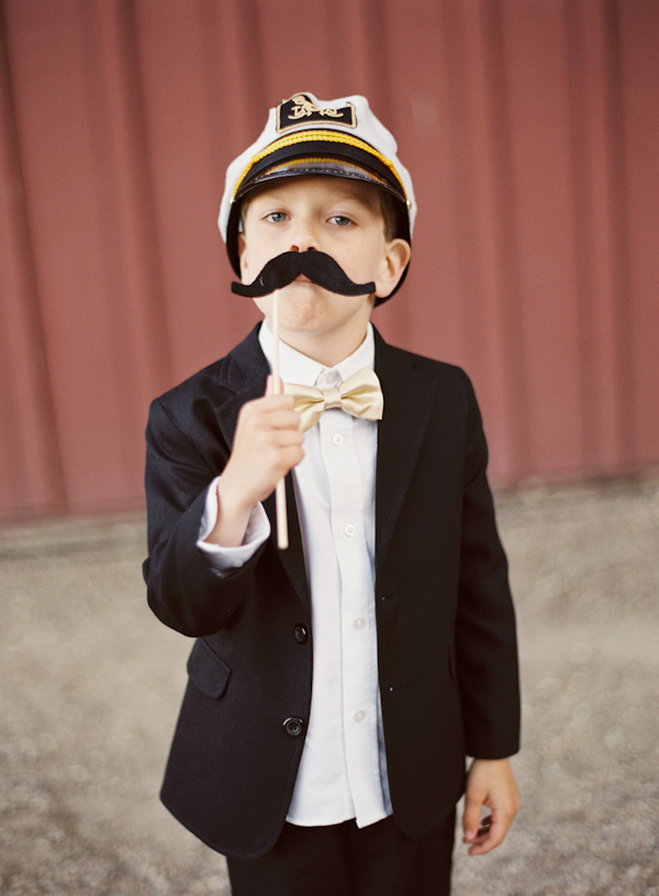 Adorable little boy in tux having fun with a mustache - Photo by Michelle Warren Photography