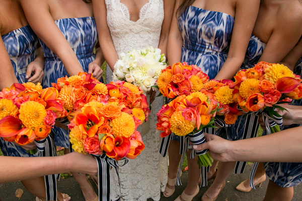 Vibrant orange bridesmaid bouquets with blue and white patterned dresses - Photo by Sarah Tew Photography