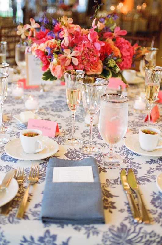 Bright pink floral centerpiece on light blue and white tablecloth with blue napkin - Photo by Sylvie Gil Photography