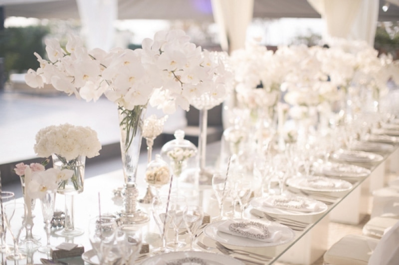 white orchid floral arrangements and place settings on long table at wedding reception, photo by Melissa Jill Photography