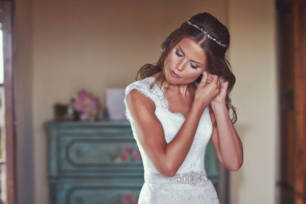 beautiful bride putting on earrings