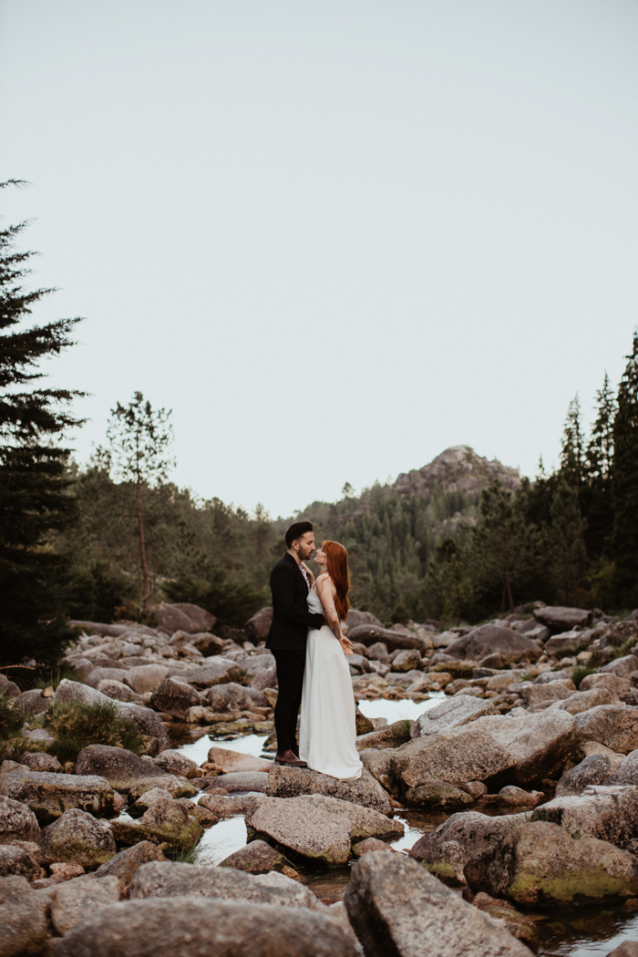 bride and groom standing on rocks