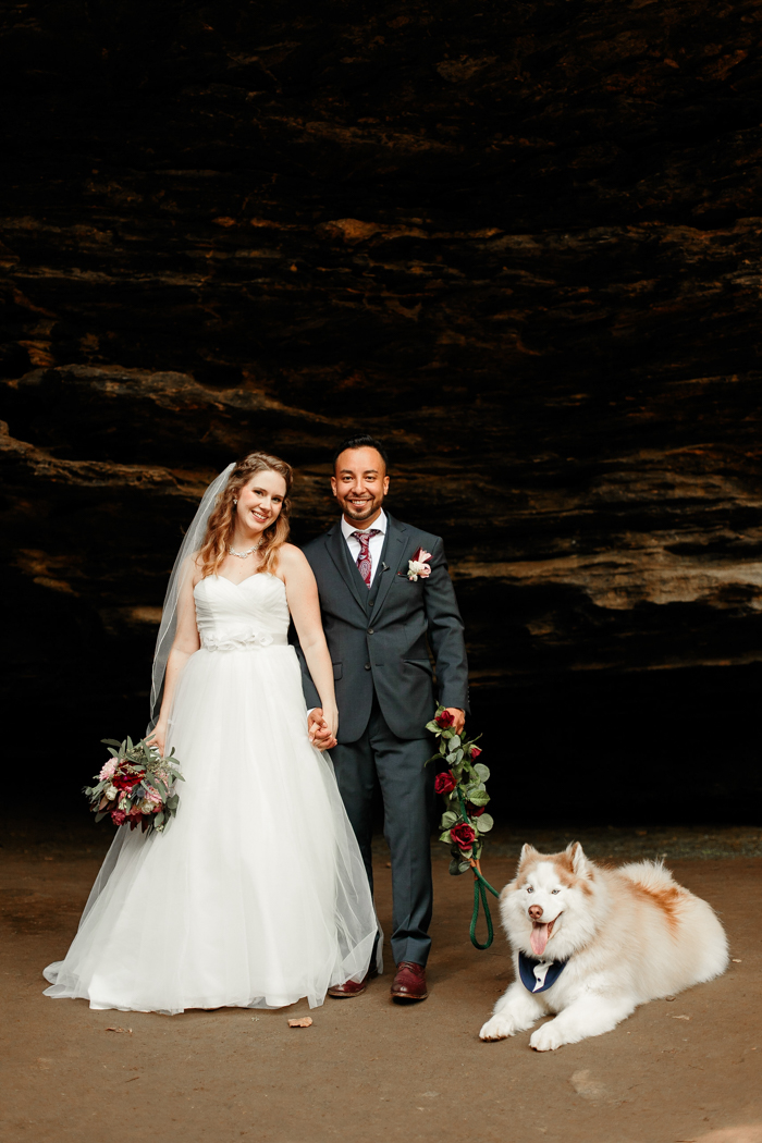 bride and groom posing together with puppy