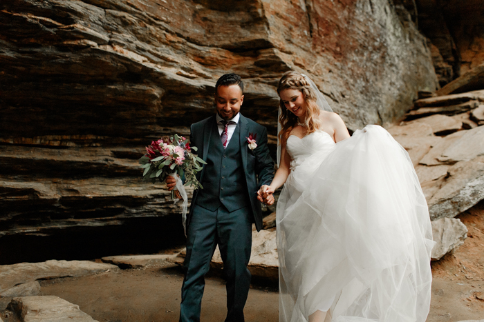 groom helping bride hike