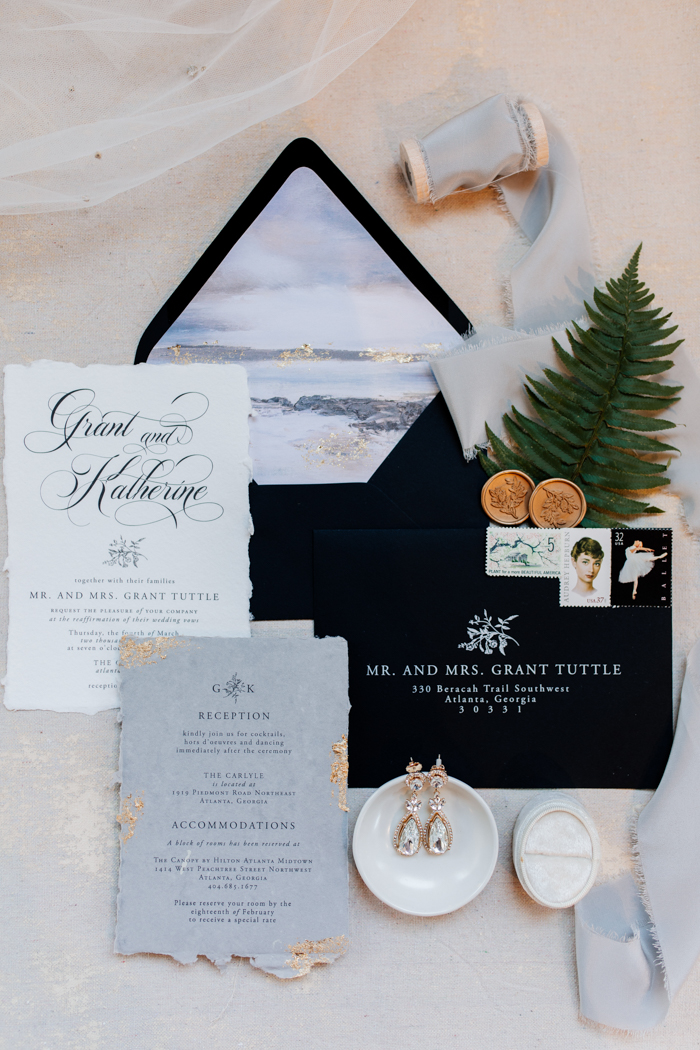 black sand beach wedding invitation suite flatlay image