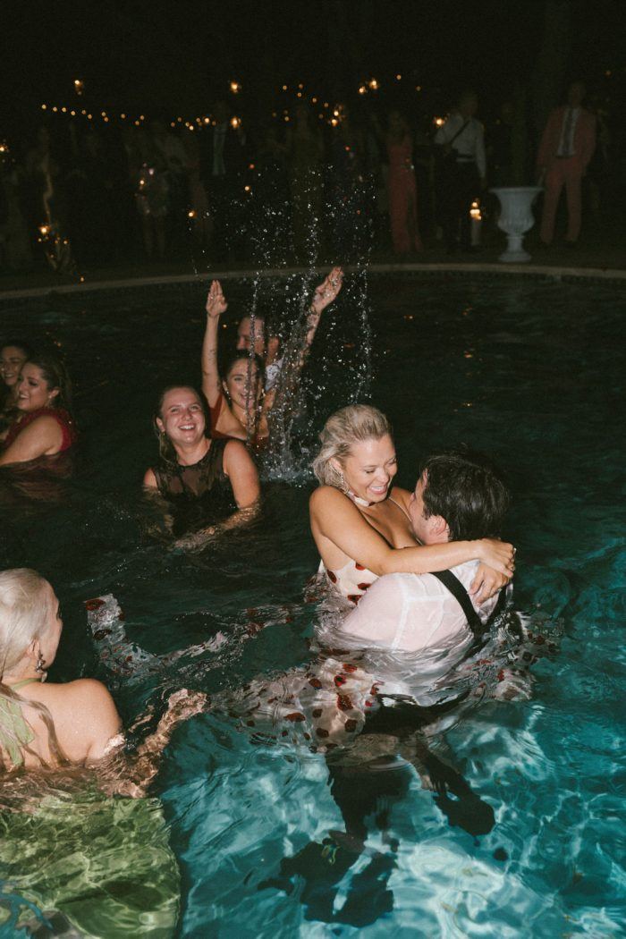 couple and wedding guests in swimming pool