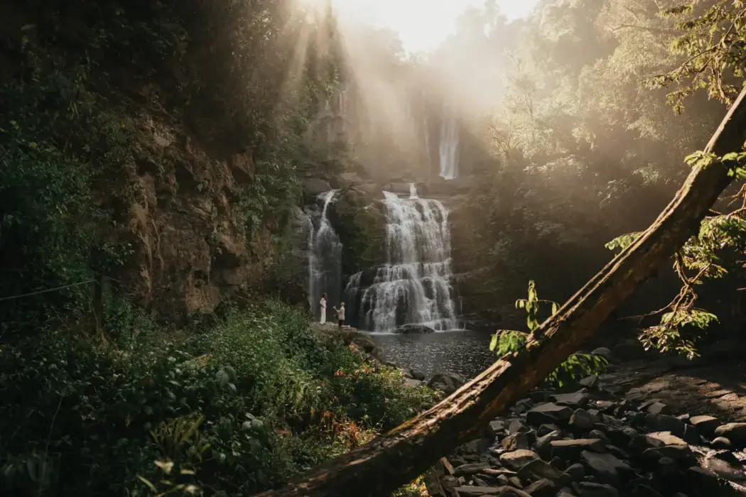 man proposing to woman in beautiful waterfall jungle