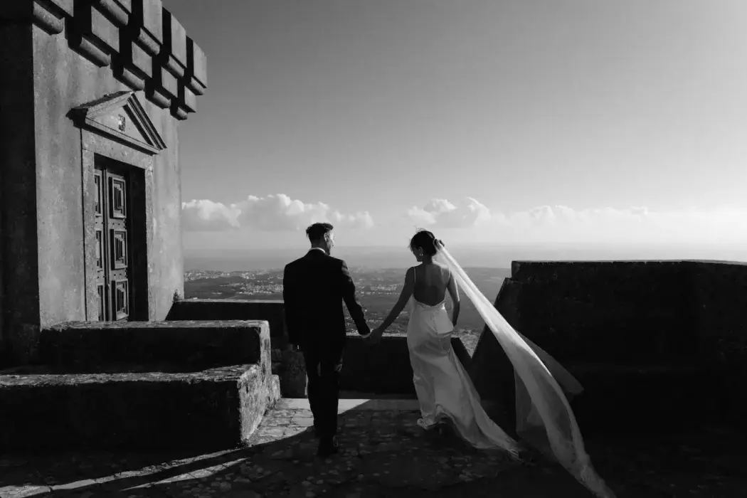 black and white photo bride and groom holding hands on roof