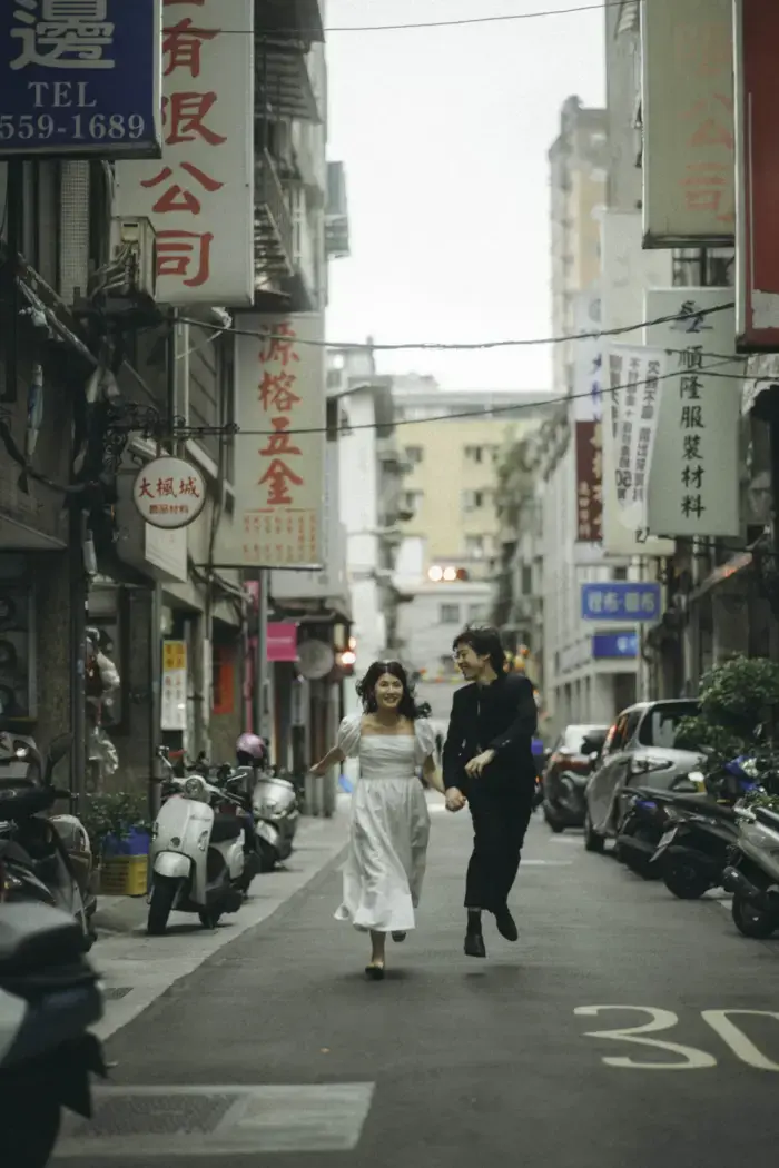 Couple holding hands running through street of Chinatown