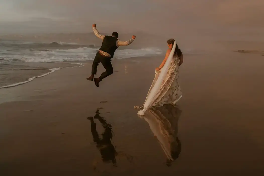 rear view of wedding couple on beach, groom clicking heels together