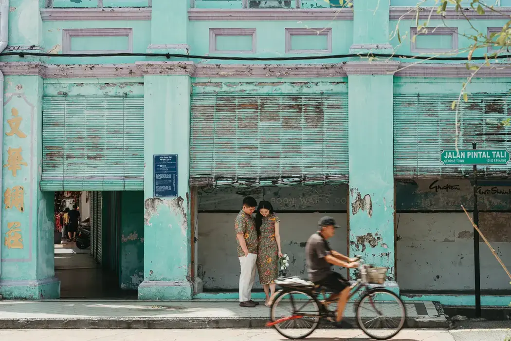colorful asian street photo, couple standing together while bicycle rides past