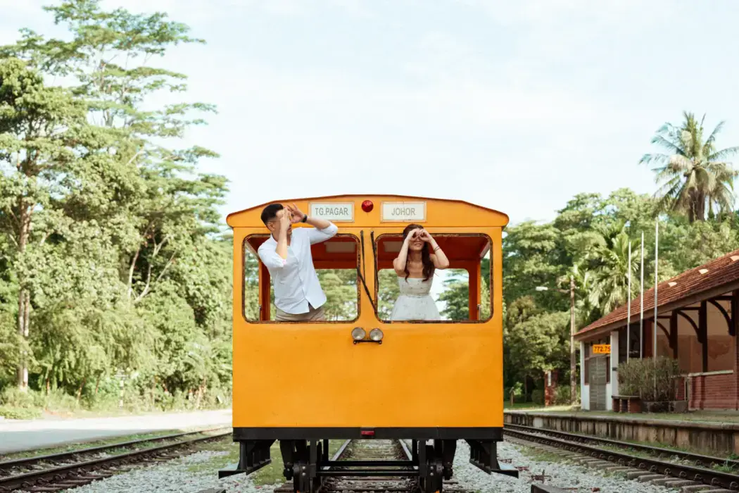 couple leaning out of yellow train car pretending to have binoculars