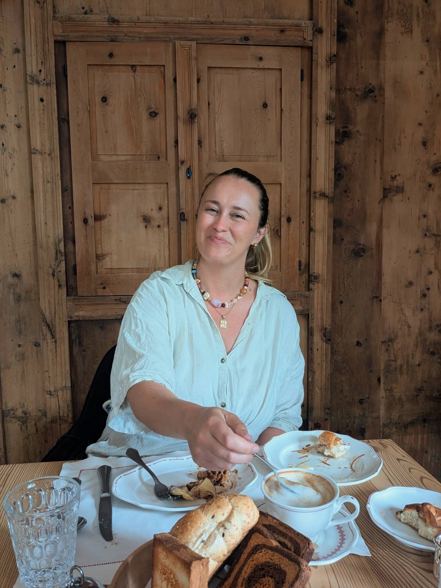Guest enjoying breakfast with pastries and a cappuccino in a wood-paneled room at Castel Badia