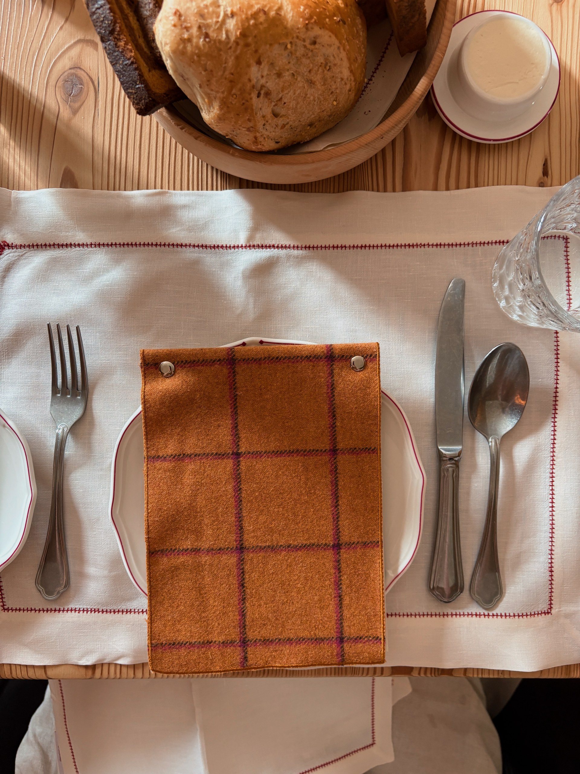 Breakfast place setting at Castel Badia with a linen placemat, a wool-covered menu, and a basket of fresh bread