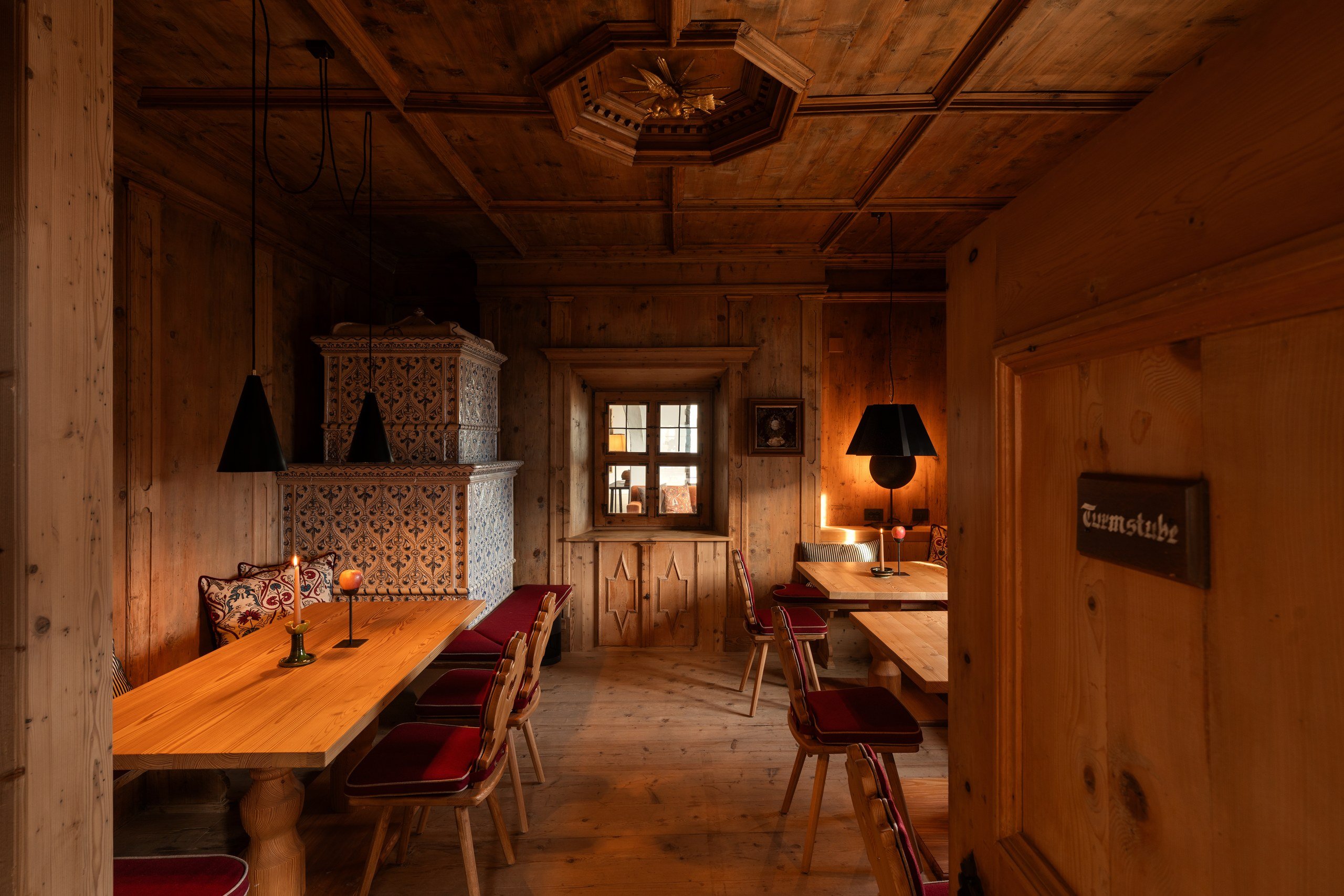 Candlelit chef's table set for a private dinner beside an open fire in a vaulted kitchen in the Dolomites